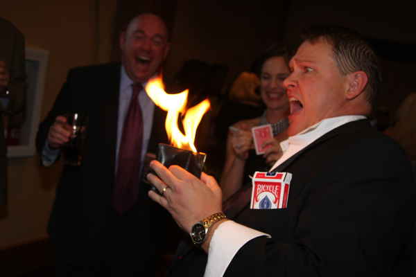 Male sleight of hand magician for parties with shocked expression on face as wallet is on fire during magic trick | Altus Entertainment
